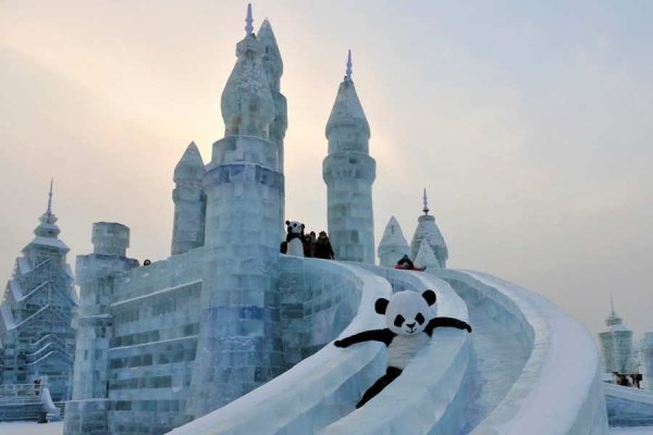 An employee wearing a panda costume slides down from an ice sculpture during the Harbin International Ice and Snow World festival in Harbin