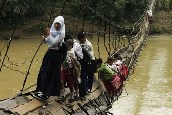 When bridges collapse from flooding or age, they must tightrope walk across them like these children are doing from Sanghiang Tanjung village.